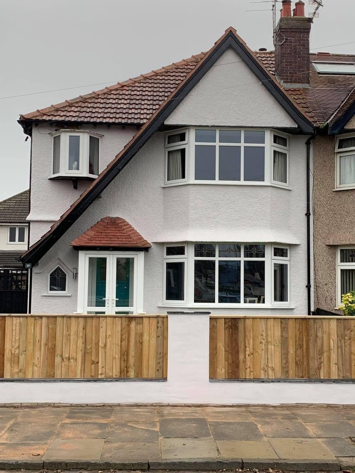 Rendered semi finished in off-white with black bargeboards, fascias and a teal front door